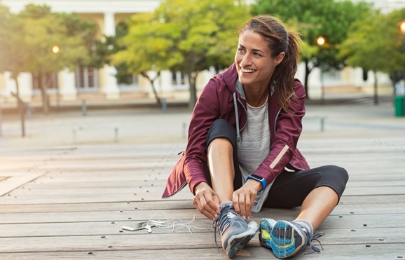 Une femme assise attache ses chaussures en souriant